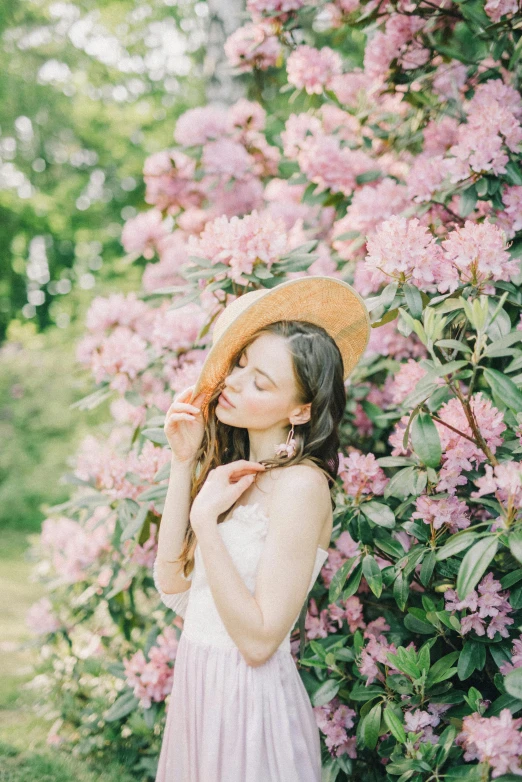 a woman standing in front of a bush of flowers, pexels contest winner, renaissance, straw hat, soft blush, anna nikonova aka newmilky, with a tall tree