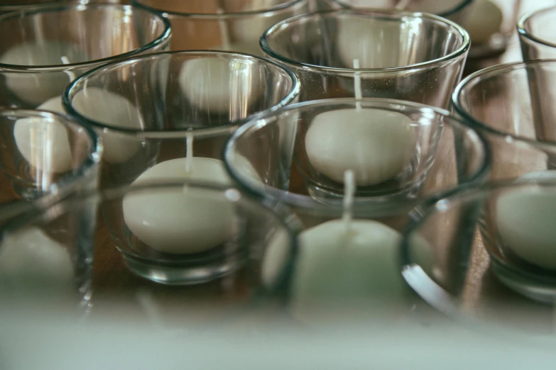 a bunch of glasses sitting on top of a wooden table, white candles, filling the frame, laura watson, carefully crafted