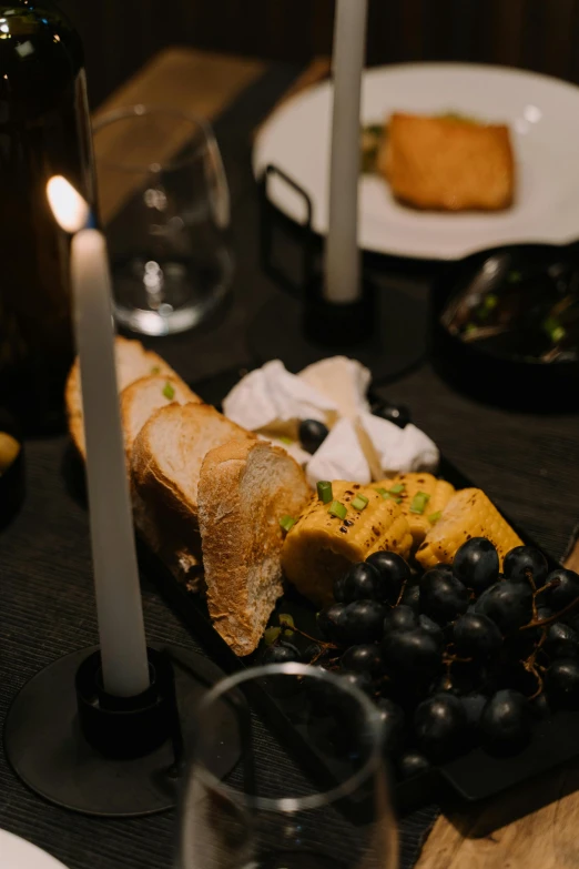 a close up of a plate of food on a table, renaissance, dark lit candles, yellow and black grapes, designed for cozy aesthetics!, creterion collection