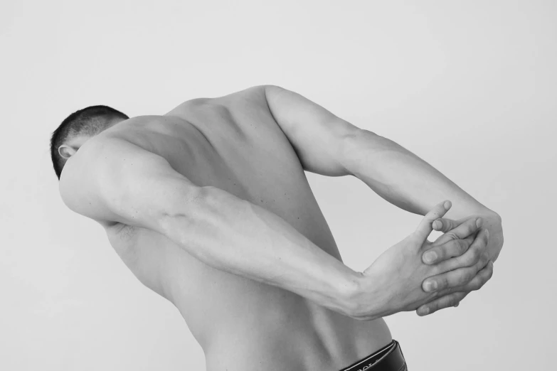 a black and white photo of a man holding his back, a black and white photo, inspired by Robert Mapplethorpe, unsplash, minimalism, 30 year old man :: athletic, ignant, cybernetic body parts, hyper realistic