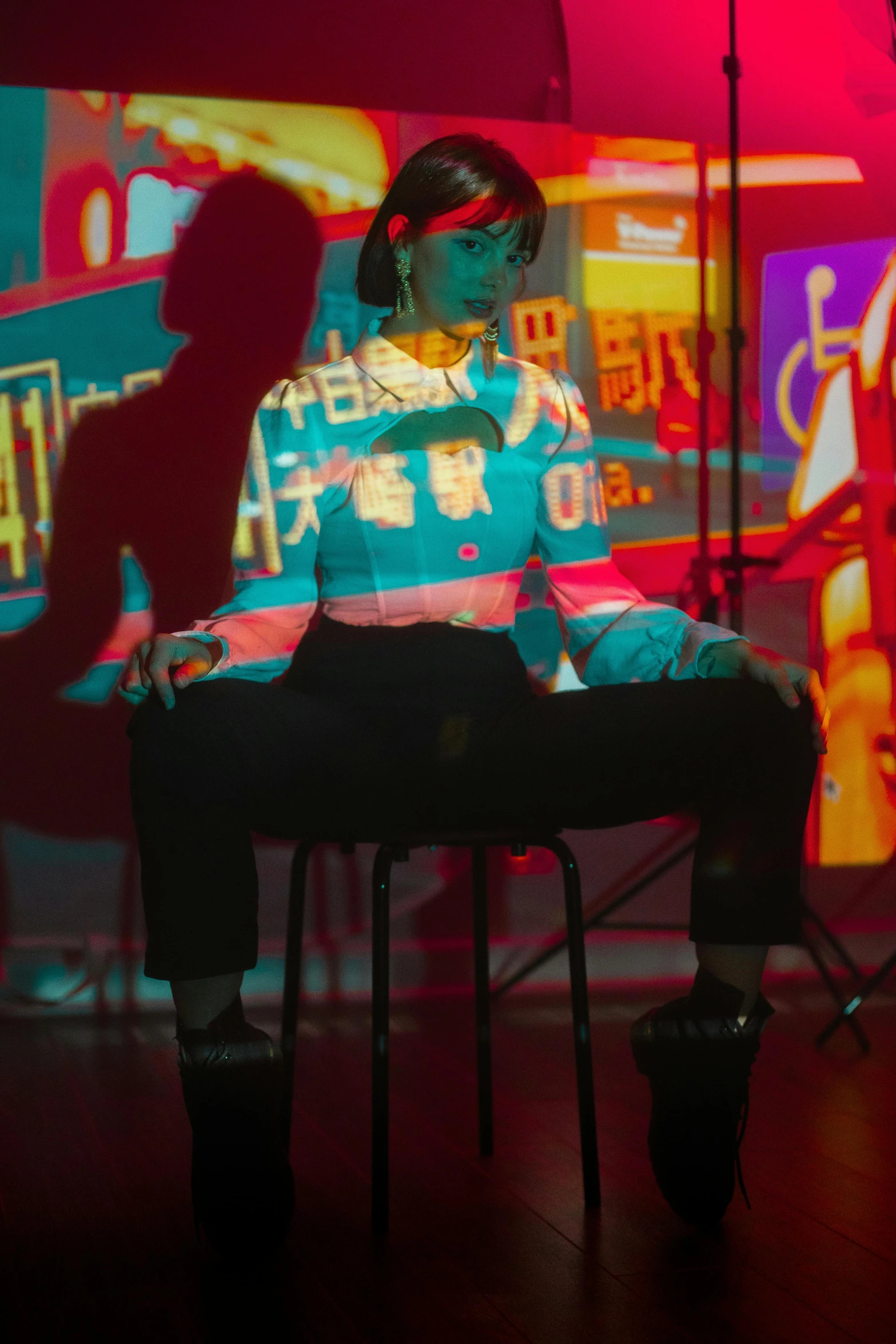 a woman sitting at a piano in a dark room, a hologram, inspired by Liam Wong, trending on pexels, holography, sitting on a stool, woman in streetwear, overlaid with chinese adverts, colorful projections