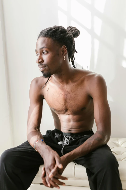 a man with dreadlocks sitting on a couch, trending on pexels, black underwear, belly button showing, ashteroth, thin aged 2 5