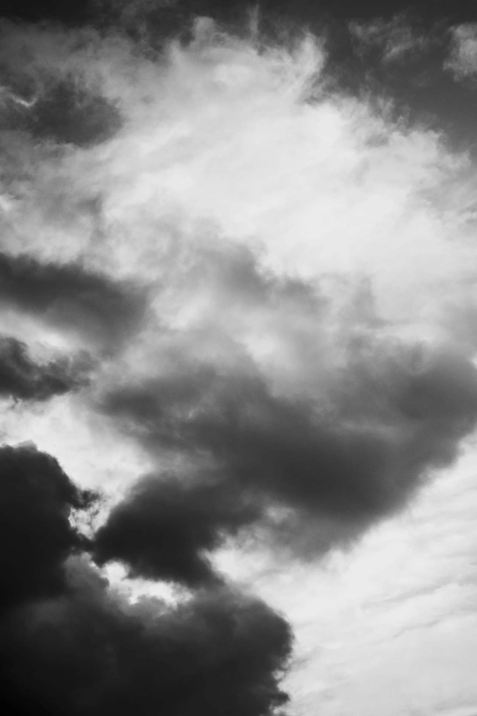 a black and white photo of a plane in the sky, inspired by Edward Weston, unsplash, vorticism, brooding clouds, ( ( abstract ) ), satanistic sky, looking threatening