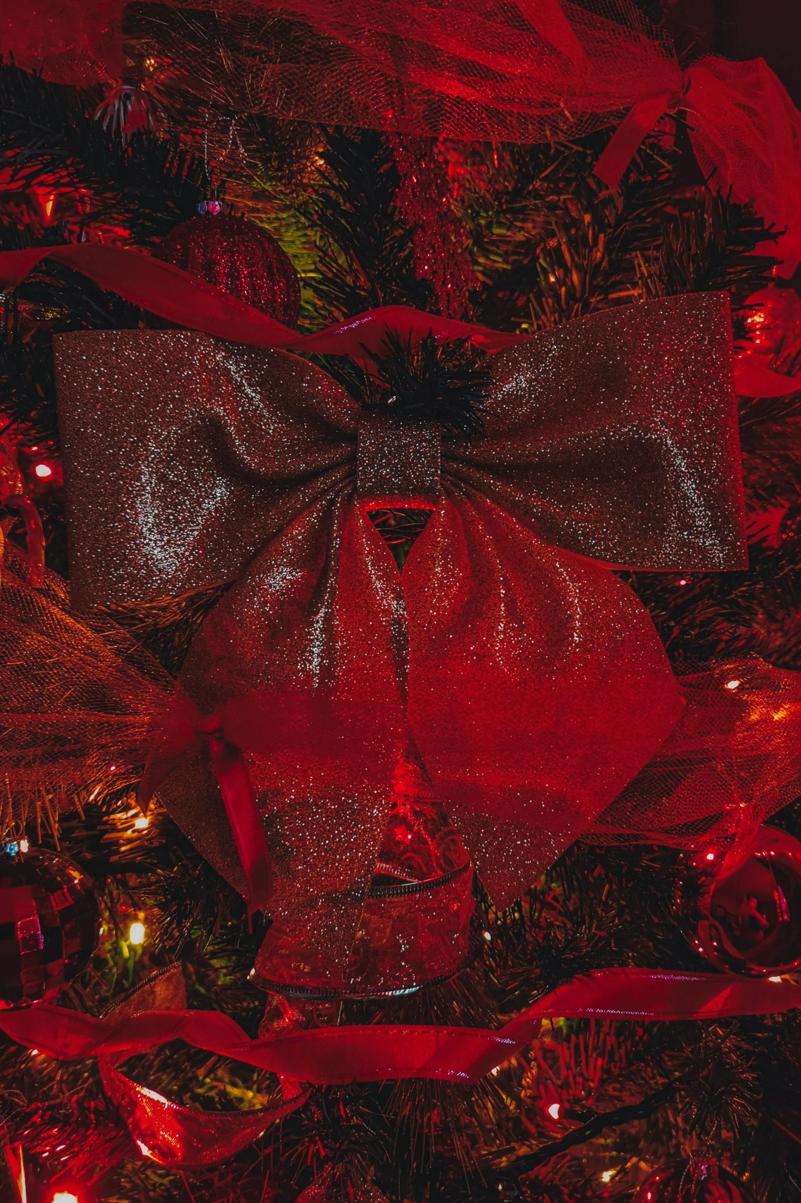 a close up of a christmas tree with a red bow, maroon metallic accents, red glow, monochromatic red, zoomed out