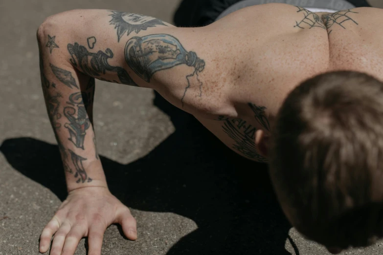 a man with tattoos doing a push up on a skateboard, a tattoo, pexels contest winner, down left arm and back, banner, heath clifford, ink on skin