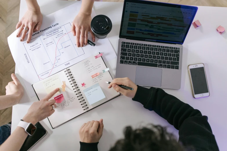 a group of people sitting at a table with laptops, pexels contest winner, schematic in a notebook, planning, 9 9 designs, product introduction photo