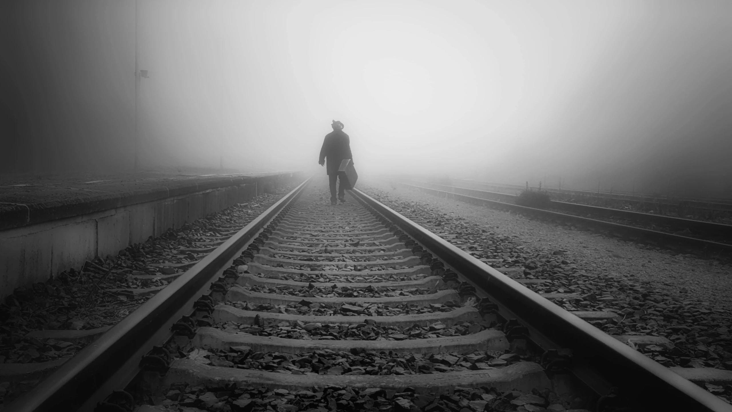 a person walking down a train track in the fog, a black and white photo, by Lucia Peka, pexels contest winner, romanticism, couple, sad man, volumetric fog, cowboy