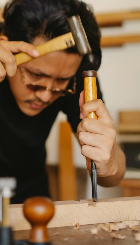 a man working on a piece of wood with a hammer, an album cover, inspired by I Ketut Soki, trending on pexels, headshot, thumbnail, student, mid shot