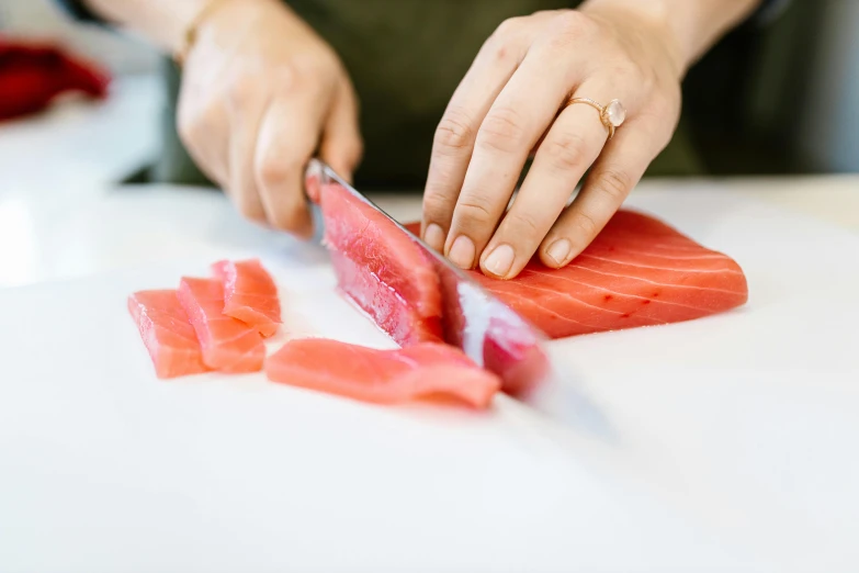 a person cutting up a piece of fish with a knife, by Julia Pishtar, trending on pexels, hurufiyya, looking off to the side, lachlan bailey, clean and pristine design, blushing