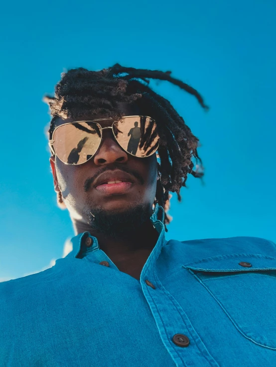 a man with dreadlocks standing in front of a blue sky, an album cover, trending on pexels, afrofuturism, wearing oakley sunglasses, 2 1 savage, maria borges, headshot profile picture