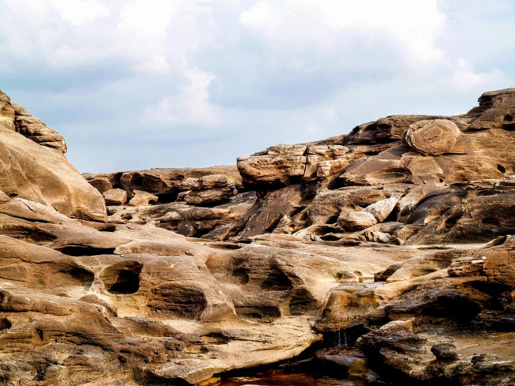 a man riding a surfboard on top of a rocky beach, an album cover, pexels contest winner, khajuraho, panorama, ((rocks)), rock texture