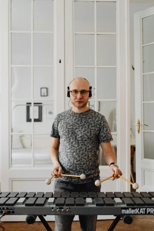 a man with headphones playing a musical instrument, an album cover, inspired by Carl Gustaf Pilo, hyperrealism, philip selway (drums), twitch streamer / gamer ludwig, low quality photo, at home