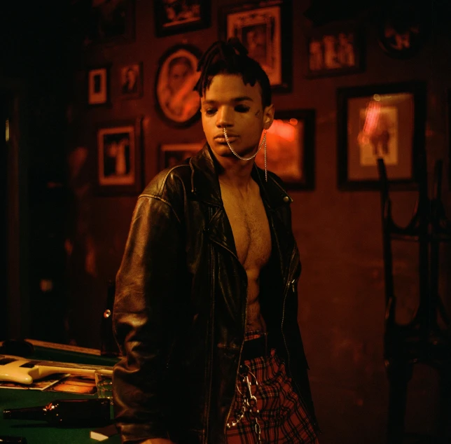 a man in a leather jacket smoking a cigarette, an album cover, inspired by Nan Goldin, trending on pexels, tessa thompson inspired, in a strip club, non binary model, loin cloth