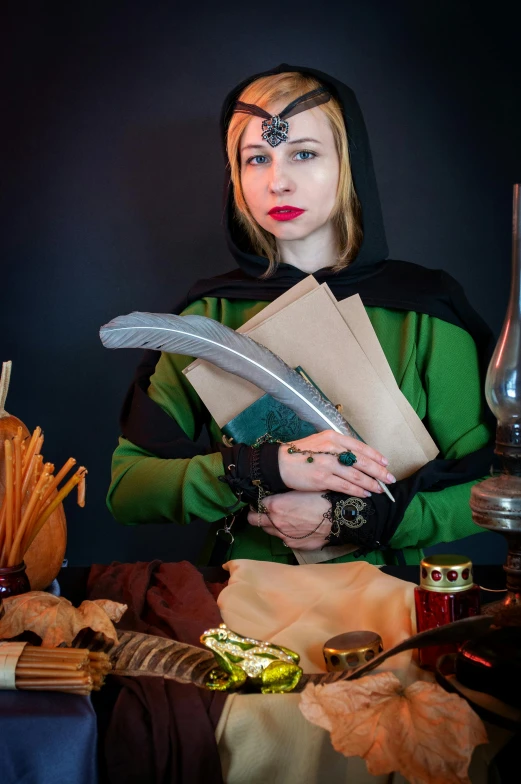 a woman sitting at a table holding a book, a character portrait, inspired by Master of the Legend of Saint Lucy, unsplash, wearing leather assassin armor, with a green cloak, holding scimitar made of bone, apothecary