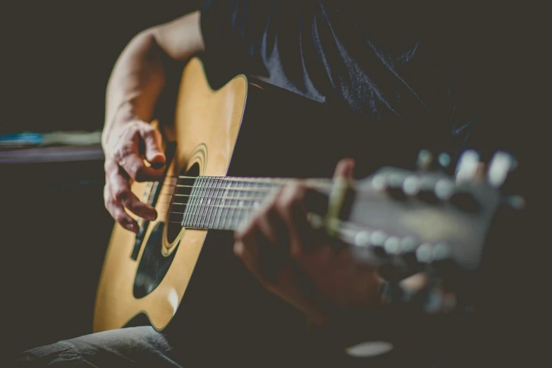 a man playing a guitar in a dark room, an album cover, pexels contest winner, soft warm light, profile image, thumbnail, faded worn