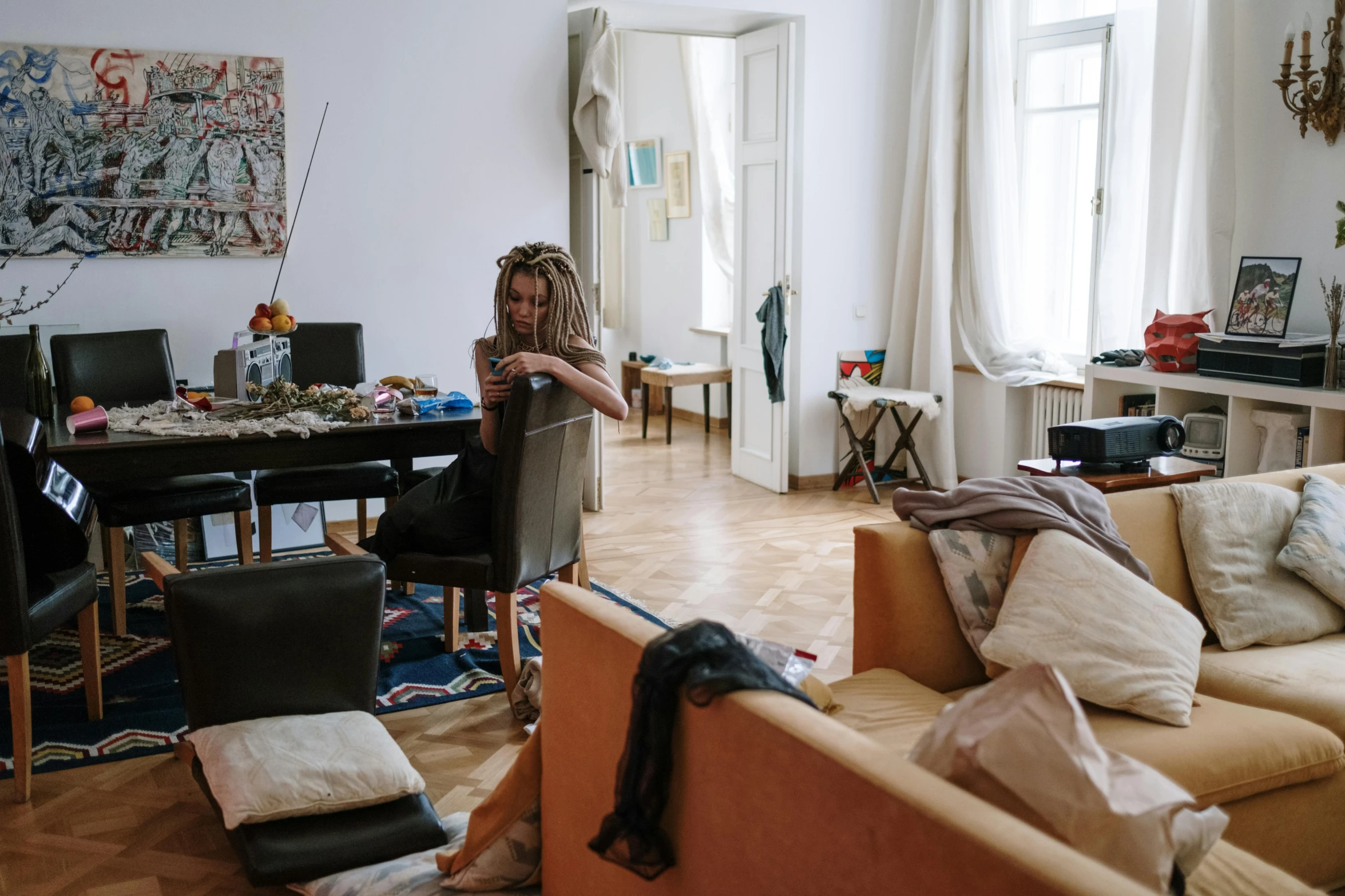 a woman sitting on a couch in a living room, arbeitsrat für kunst, messy cords, vienna secesion style, busy but lonely, airbnb