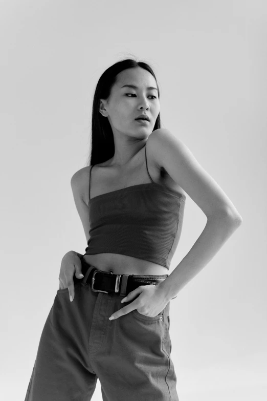 a woman standing with her hands on her hips, a black and white photo, inspired by Wang E, trending on pexels, wearing a cropped top, like a catalog photograph, utility, louise zhang