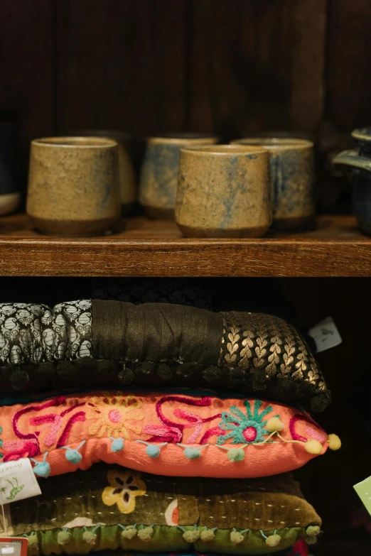 a shelf filled with lots of different types of fabric, a still life, trending on unsplash, cloisonnism, cups and balls, middle eastern details, pillows, warm glow