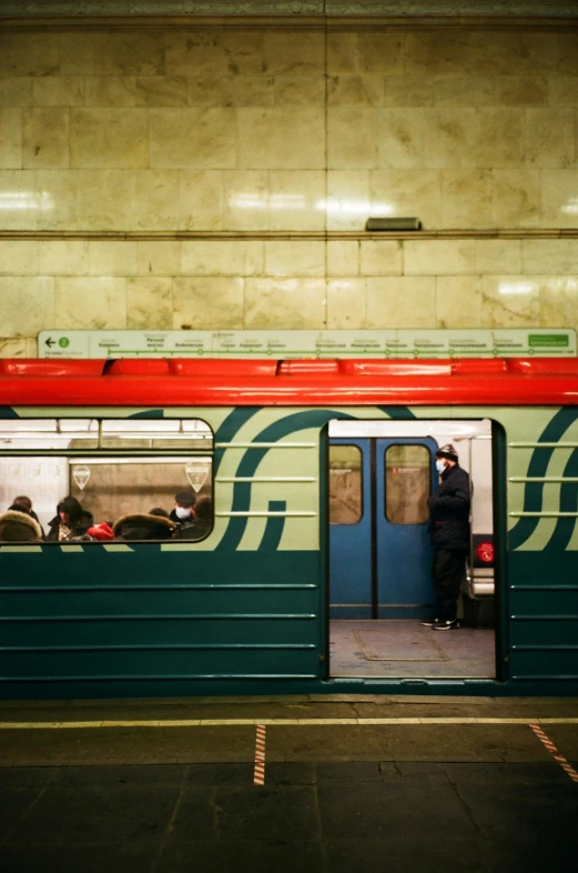 a red and green train sitting inside of a train station, flickr, socialist realism, moscow metro, a man, 15081959 21121991 01012000 4k, square lines