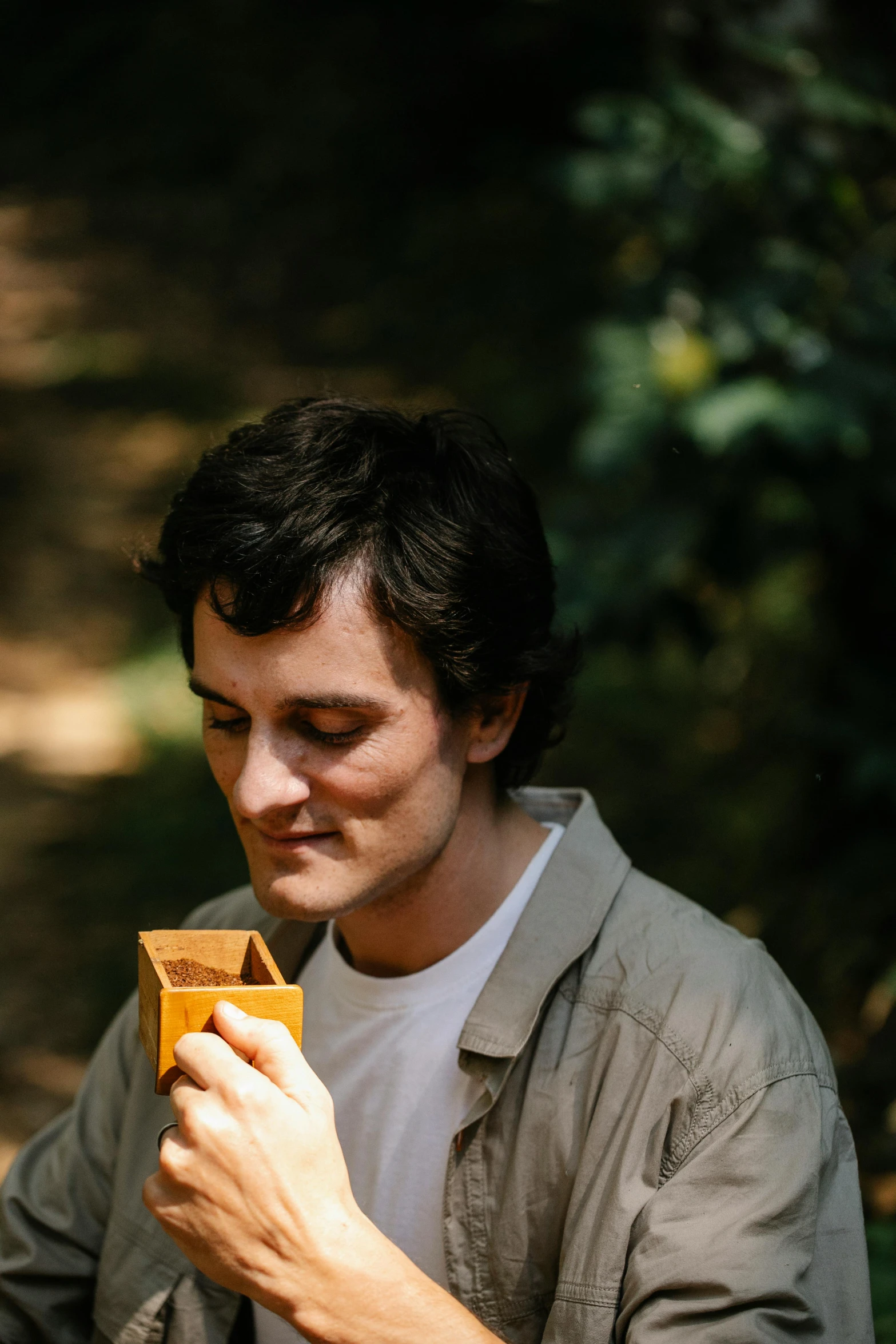 a man that is sitting down with a cell phone, an album cover, unsplash, in the wood, adam ondra, drinking tea, close-up portrait film still