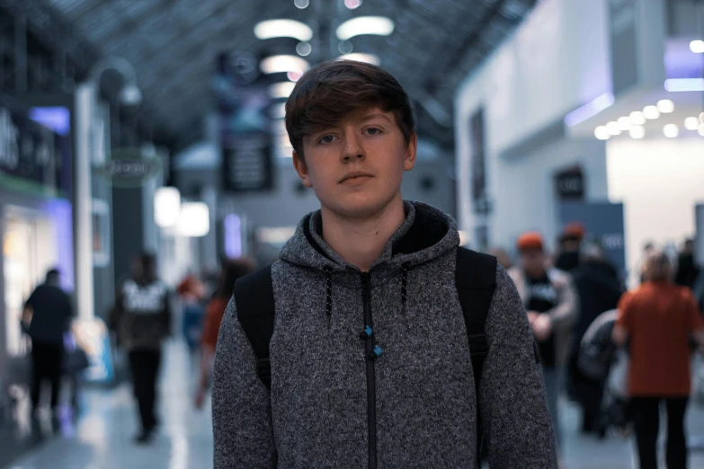 a young man with a backpack standing in a building, reddit, hyperrealism, irish youtuber, taken with sony alpha 9, in a mall, boyish face