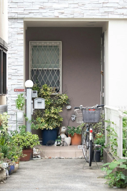 a bicycle is parked in front of a house, by Miyamoto, potted plants, grey, arasaka, entrance