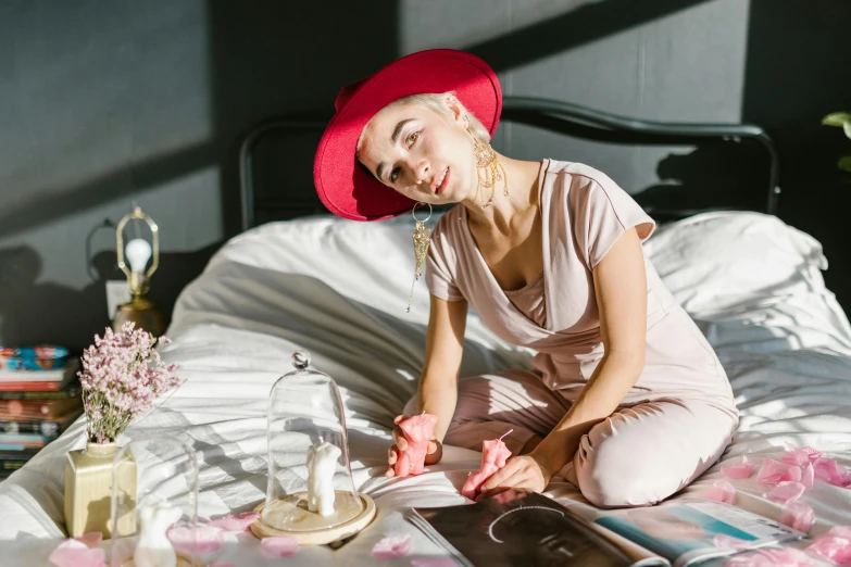 a woman sitting on a bed reading a book, a portrait, by Julia Pishtar, trending on pexels, red hat, pink clothes, writing a letter, sydney sweeney