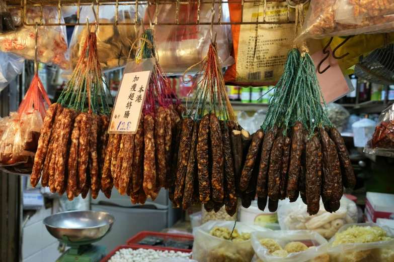 a market filled with lots of different types of food, hanging veins, sausage, jen zee, made of glazed