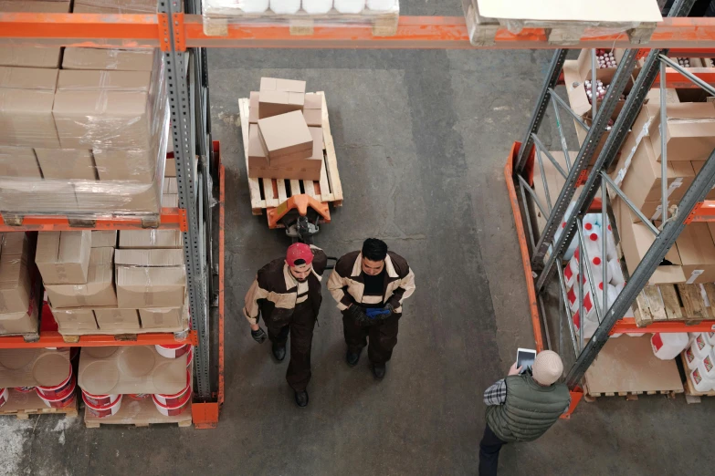 a group of men standing next to each other in a warehouse, pexels contest winner, ariel view, carrying a tray, thumbnail, inspect in inventory image