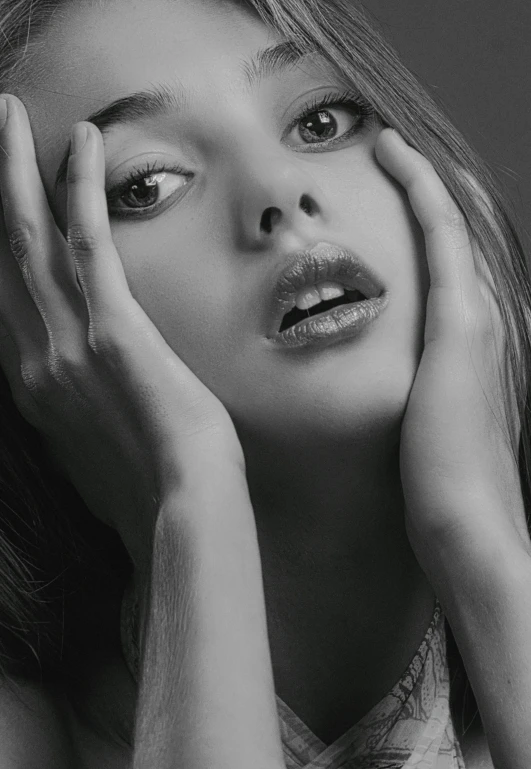 a black and white photo of a woman with her hands on her face, supermodel! face!, desaturated, smooth in _ the background, young woman's face