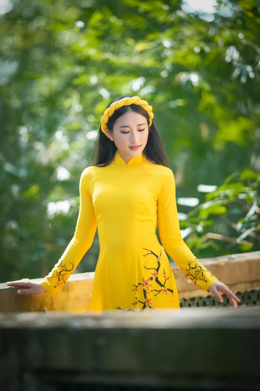 a woman in a yellow dress standing on a bridge, inspired by Tang Di, happening, ao dai, square, 5 0 0 px models, long sleeves