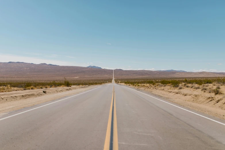 an empty road in the middle of the desert, an album cover, unsplash, ignant, broadway, panoramic photography, cloudless sky