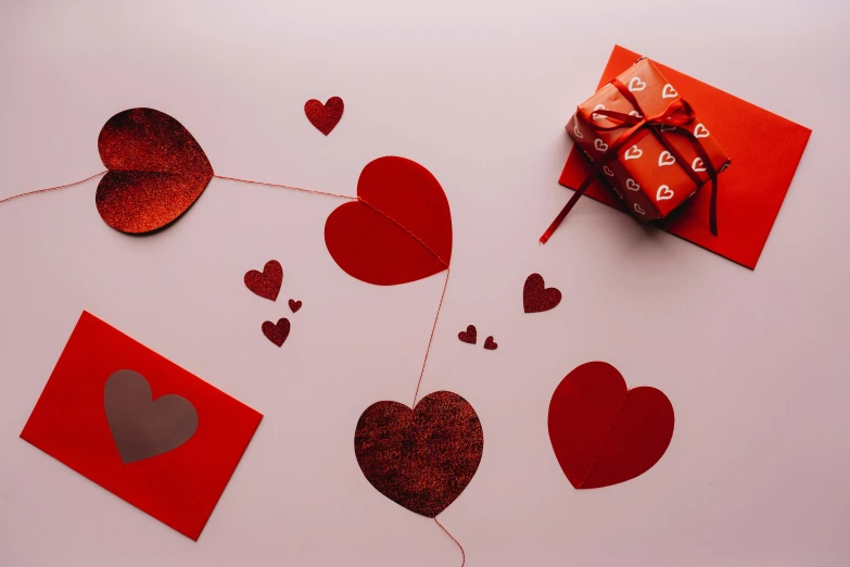a red gift box sitting on top of a white table, a cartoon, by Julia Pishtar, pexels contest winner, romanticism, several hearts, brown, diecut, foil