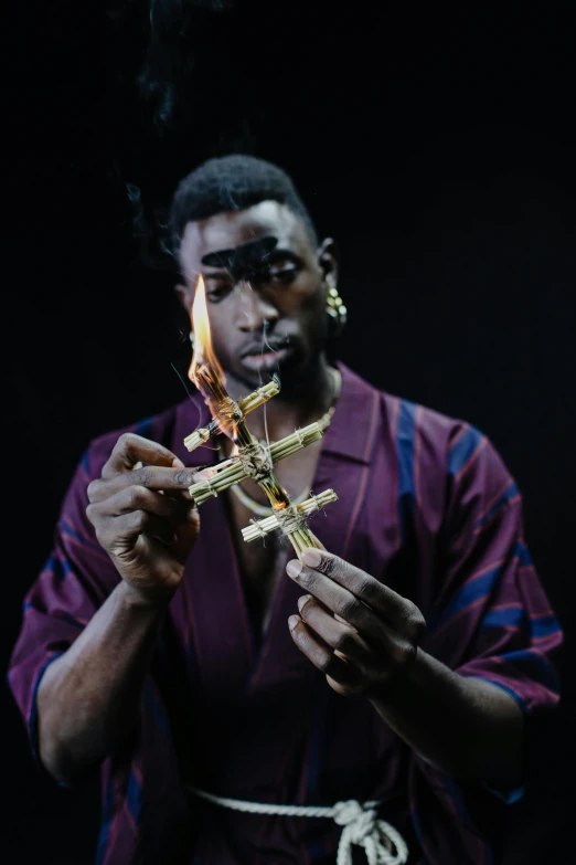 a man that is holding a cross in his hand, an album cover, inspired by Godfrey Blow, pexels contest winner, afrofuturism, casting a flame spell, playboi carti portrait, glass and gold pipes, kayne west