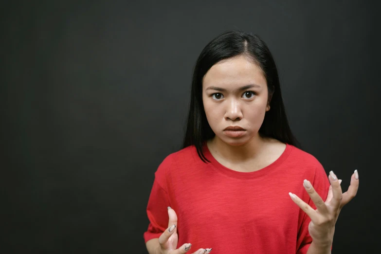 a woman holding her hands in front of her face, pexels, realism, red shirt, annoyed expression, asian, square