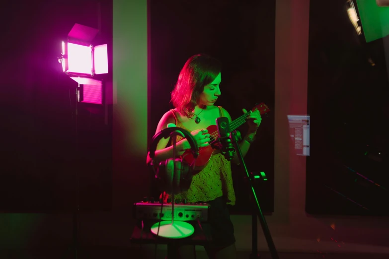 a woman playing a guitar in a dimly lit room, happening, fuschia leds, with robotic arms, acoustic information, instagram photo