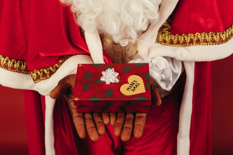 a close up of a santa claus holding a gift, an album cover, pexels, wearing long royal robe, single pair of hands, ( ( dark skin ) ), leaked image