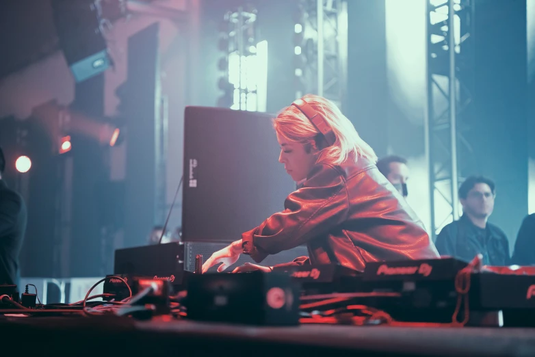 a woman sitting at a table in front of a laptop computer, unsplash, process art, dj rave party, blonde, performing on stage, xqc