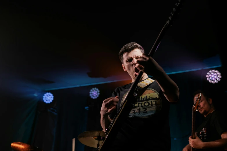 a man holding a guitar on top of a stage, by Matt Cavotta, pexels contest winner, realism, movie still of a snarling, static noise, band, rectangle