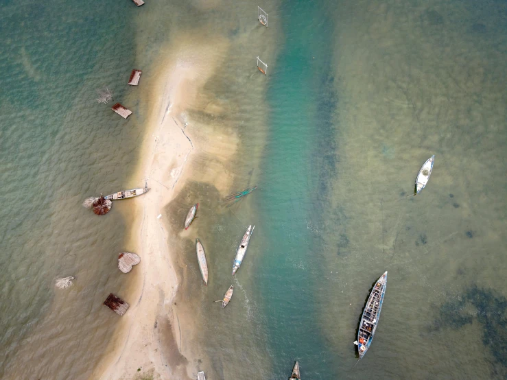 a group of boats floating on top of a body of water, by Jessie Algie, pexels contest winner, hurufiyya, dredged seabed, air shot, shoreline, thumbnail