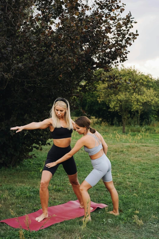 a couple of women standing on top of a pink mat, by Emma Andijewska, unsplash, renaissance, cottagecore!! fitness body, standing in grassy field, wearing fitness gear, blonde