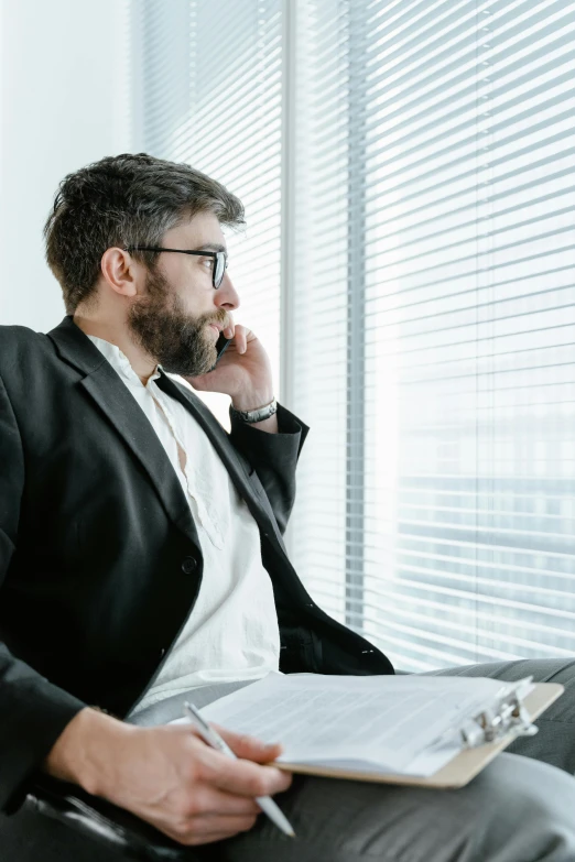 a man sitting in a chair talking on a cell phone, looking out a window, lawyer clothing, charts, the best