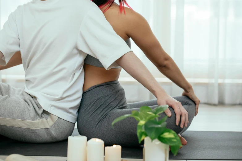 a man and a woman sitting on a yoga mat, showing her shoulder from back, sydney park, low quality photo, woman holding another woman