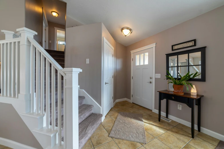 a hallway with stairs, a table, and a mirror, a picture, listing image