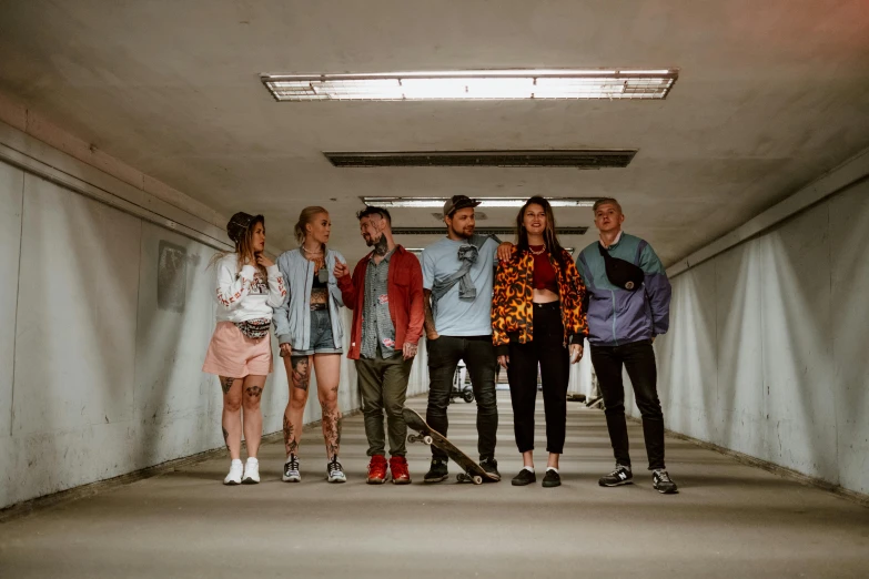 a group of people standing next to each other in a tunnel, pexels contest winner, antipodeans, with pop punk style, colourful clothing, on the concrete ground, zig zag