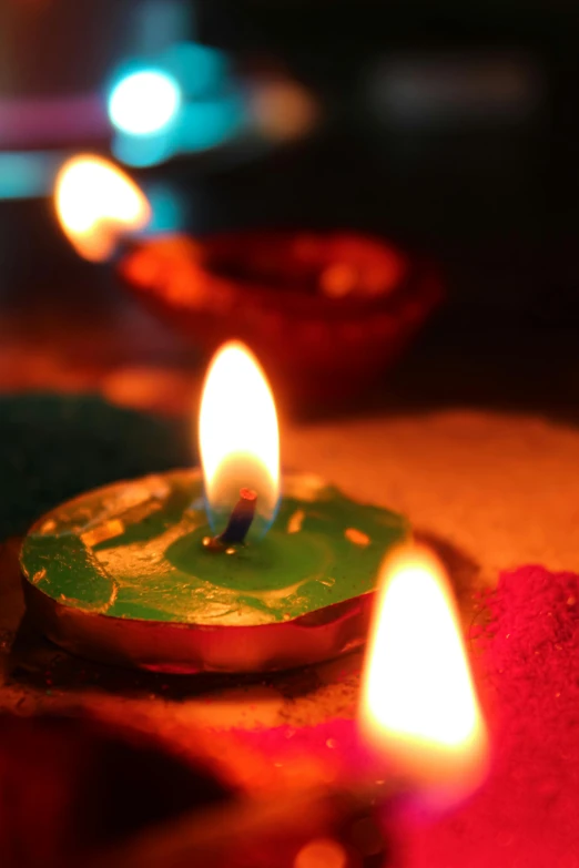 a group of lit candles sitting on top of a table, hindu ornaments, glowing dust, brightly coloured, avatar image