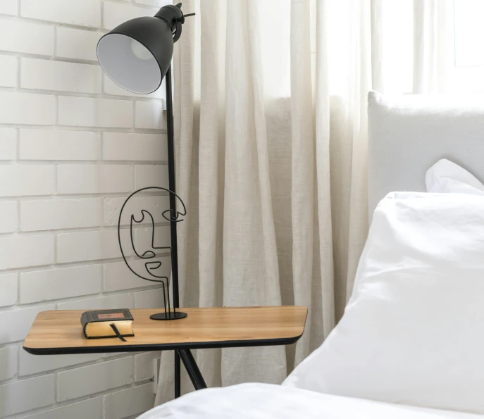 a lamp sitting on top of a wooden table next to a bed, inspired by Saul Steinberg, figuration libre, angle face, medium height, made of wrought iron, product introduction photo