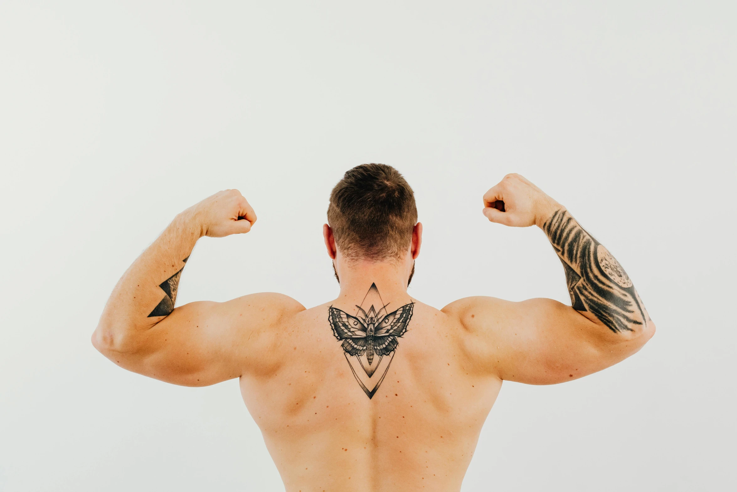 a man with a tattoo on his back, pexels contest winner, big biceps, symmetrical wings on back, lachlan bailey, mesomorph