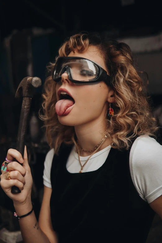 a woman sticking her tongue out in front of a microphone, an album cover, inspired by Jules Chéret, trending on pexels, happening, female blacksmith, goggles, ( waitress ) girl, 2019 trending photo