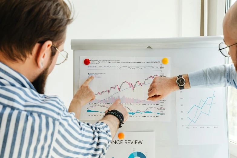 two men looking at a white board with graphs on it, trending on unsplash, 🦩🪐🐞👩🏻🦳, australia, holding a clipboard, middle shot